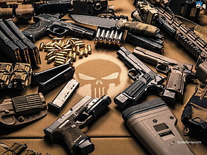 Tactical Firearms and Ammunition Arranged Around Punisher Skull Emblem on Tan Fabric HD wallpaper