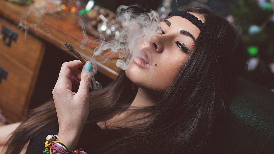 Woman with braided headband smoking a joint with swirling smoke in a cozy indoor setting HD wallpaper
