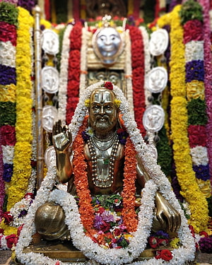 Guru Raghavendra Swamy Murti Adorned With Vibrant Flower Garlands In Temple Setting HD phone wallpaper