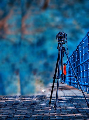 DSLR Camera on Tripod on Cobblestone Path with Blue Bokeh Background HD phone wallpaper