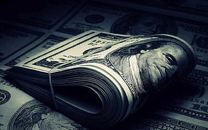 Stack of US Dollar Bills with Benjamin Franklin Portrait in Dark Moody Lighting HD wallpaper