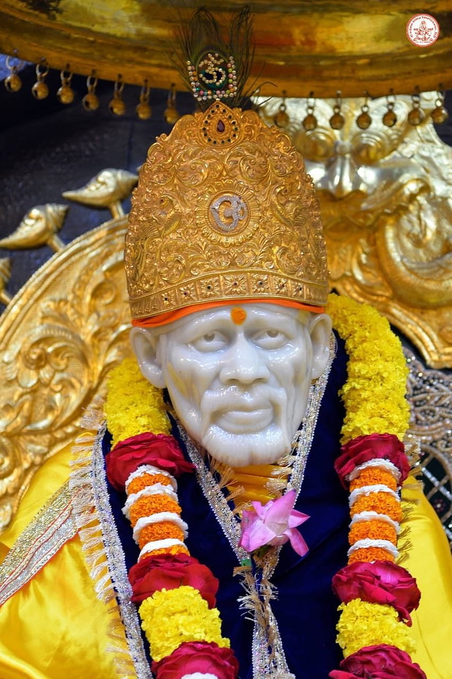 Ornate Shirdi Sai Baba Statue Adorned With Golden Crown And Vibrant Floral Garlands HD phone wallpaper
