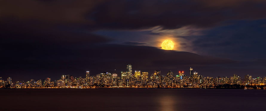 Full Moon Rising Over a Glowing City Skyline at Night HD wallpaper