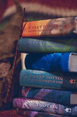 Stacked Harry Potter Hardcover Books with Wand and Warm Cozy Lighting HD phone wallpaper