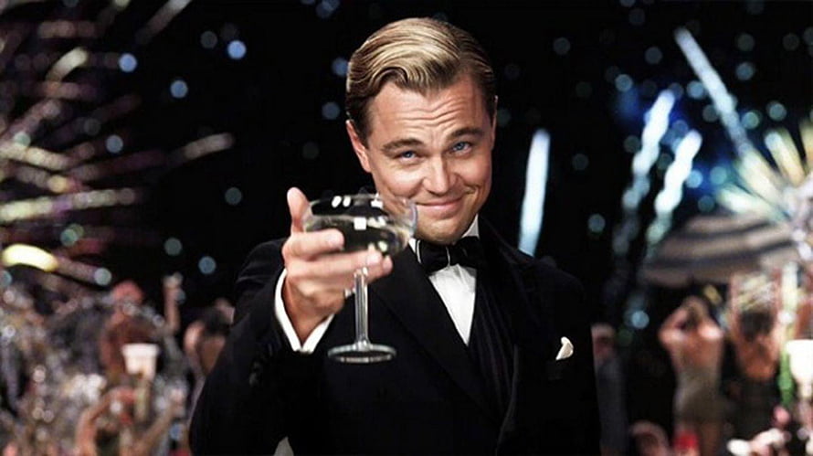 Leonardo DiCaprio as Jay Gatsby in The Great Gatsby holding a champagne glass at a lavish party HD wallpaper