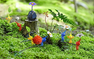 Pikmin 3 Characters Exploring a Vibrant Mossy Forest with Tiny Flowers and a Large Berry HD wallpaper