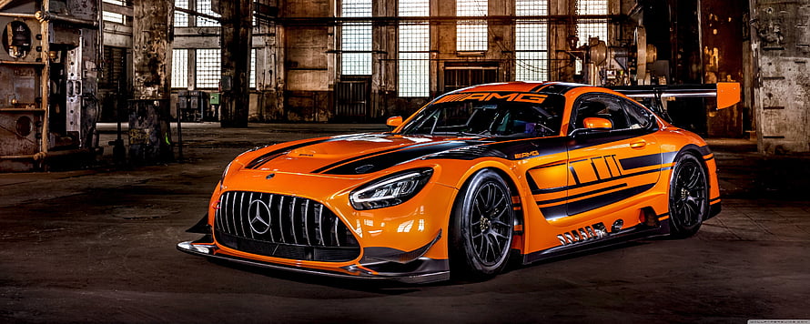 Orange Mercedes-AMG GT3 race car with black livery parked in an industrial warehouse HD wallpaper