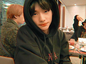 Hwang Hyunjin of Stray Kids in a black hoodie at a casual indoor gathering HD wallpaper