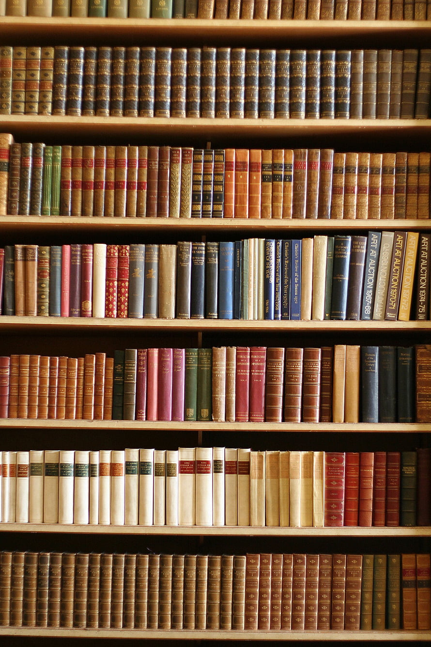 Vintage leather-bound books neatly arranged on wooden library shelves HD phone wallpaper