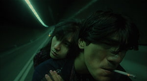 Wong Kar Wai cinematic still of a couple in a dimly lit tunnel with moody green tones HD wallpaper