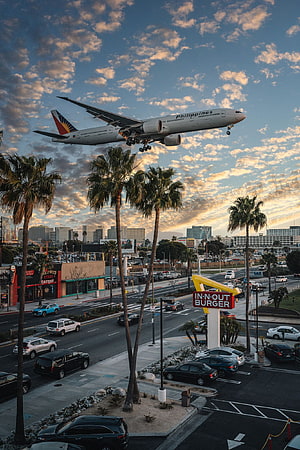 Philippines Airline Jet Descending Over Los Angeles Cityscape at Sunset HD phone wallpaper