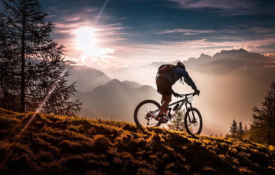 Mountain Biker Silhouette on Alpine Ridge at Golden Hour Sunset HD wallpaper