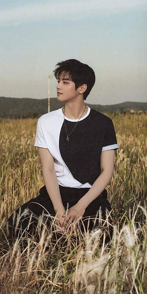 Cha Eun Woo of Astro Sitting in a Golden Grass Field Wearing a Black and White Shirt HD phone wallpaper