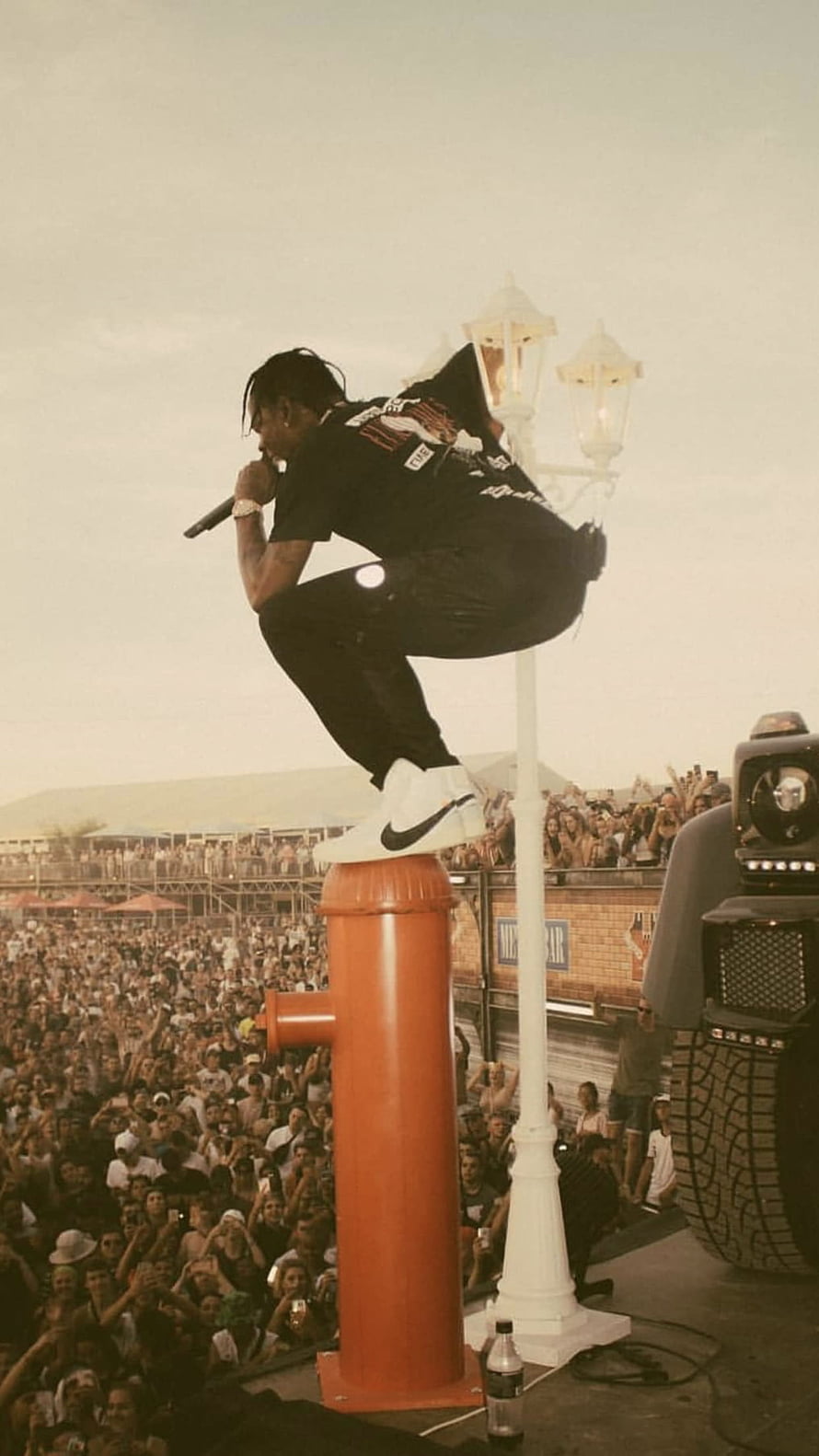 Travis Scott performing live on stage at a massive outdoor music festival HD phone wallpaper