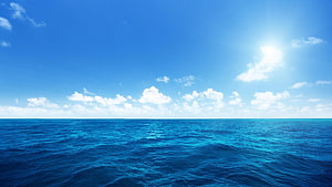 Vast Open Ocean Horizon Under a Bright Blue Sky with Scattered Clouds HD wallpaper