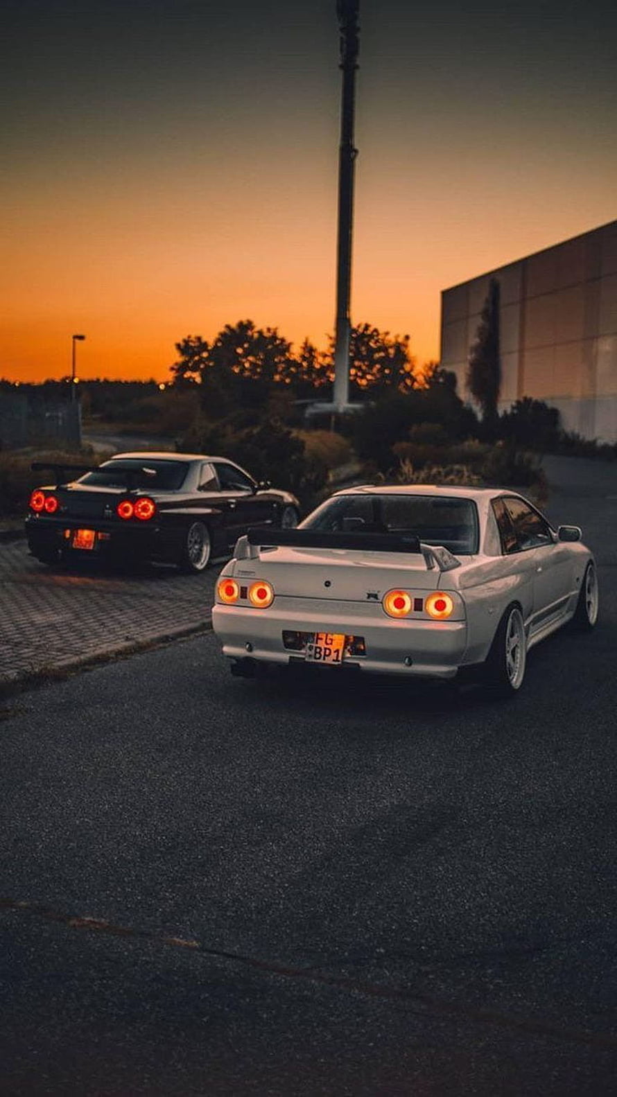 Silver Nissan Skyline GT-R R32 and Black R32 at Sunset in a Parking Lot HD phone wallpaper