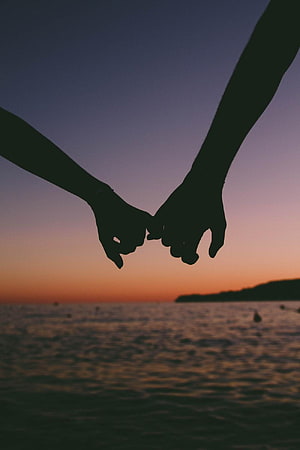 Silhouetted Couple Holding Hands Against a Warm Ocean Sunset HD phone wallpaper