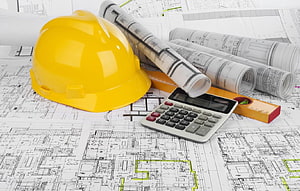 Yellow hard hat, rolled blueprints, calculator, and level on architectural plans HD wallpaper