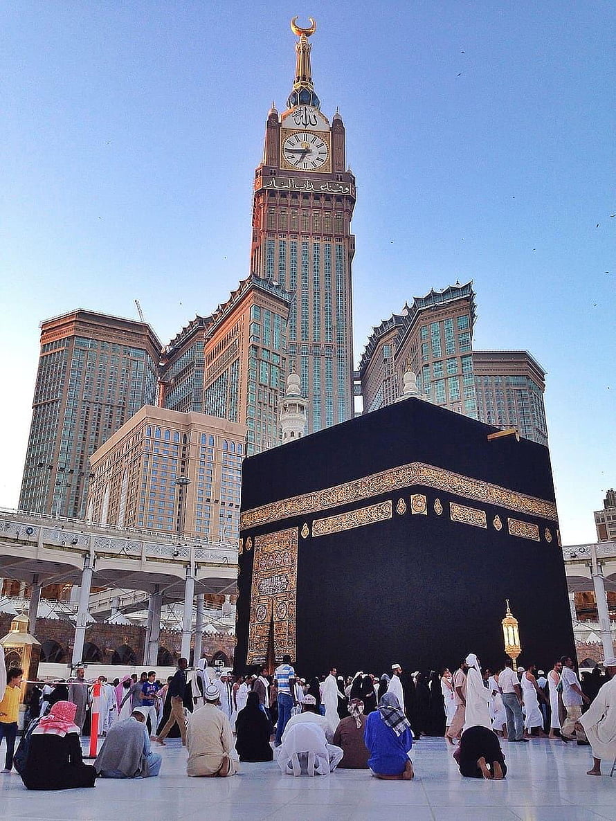 The Kaaba in Makkah with the Makkah Clock Tower and pilgrims in prayer HD phone wallpaper