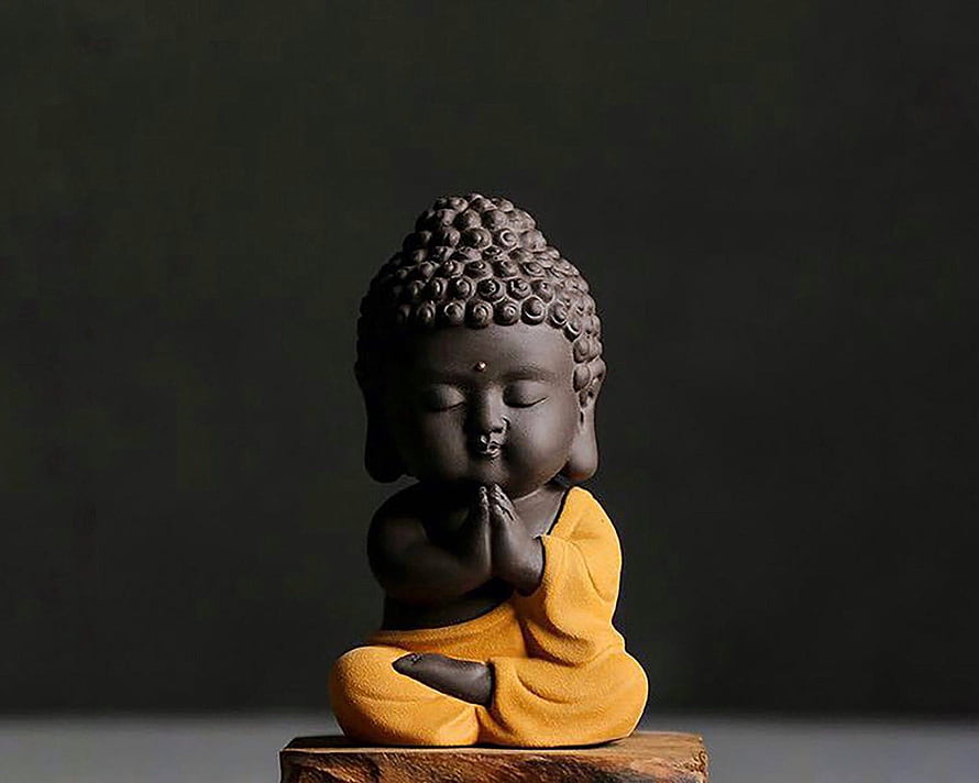 Cute Chibi Buddha Statue in Yellow Robe with Praying Hands on Wooden Base HD wallpaper