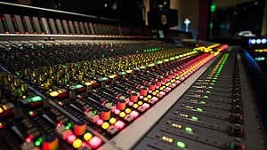 Professional Audio Mixing Console with Glowing Faders and Illuminated Control Buttons in a Dark Recording Studio HD wallpaper