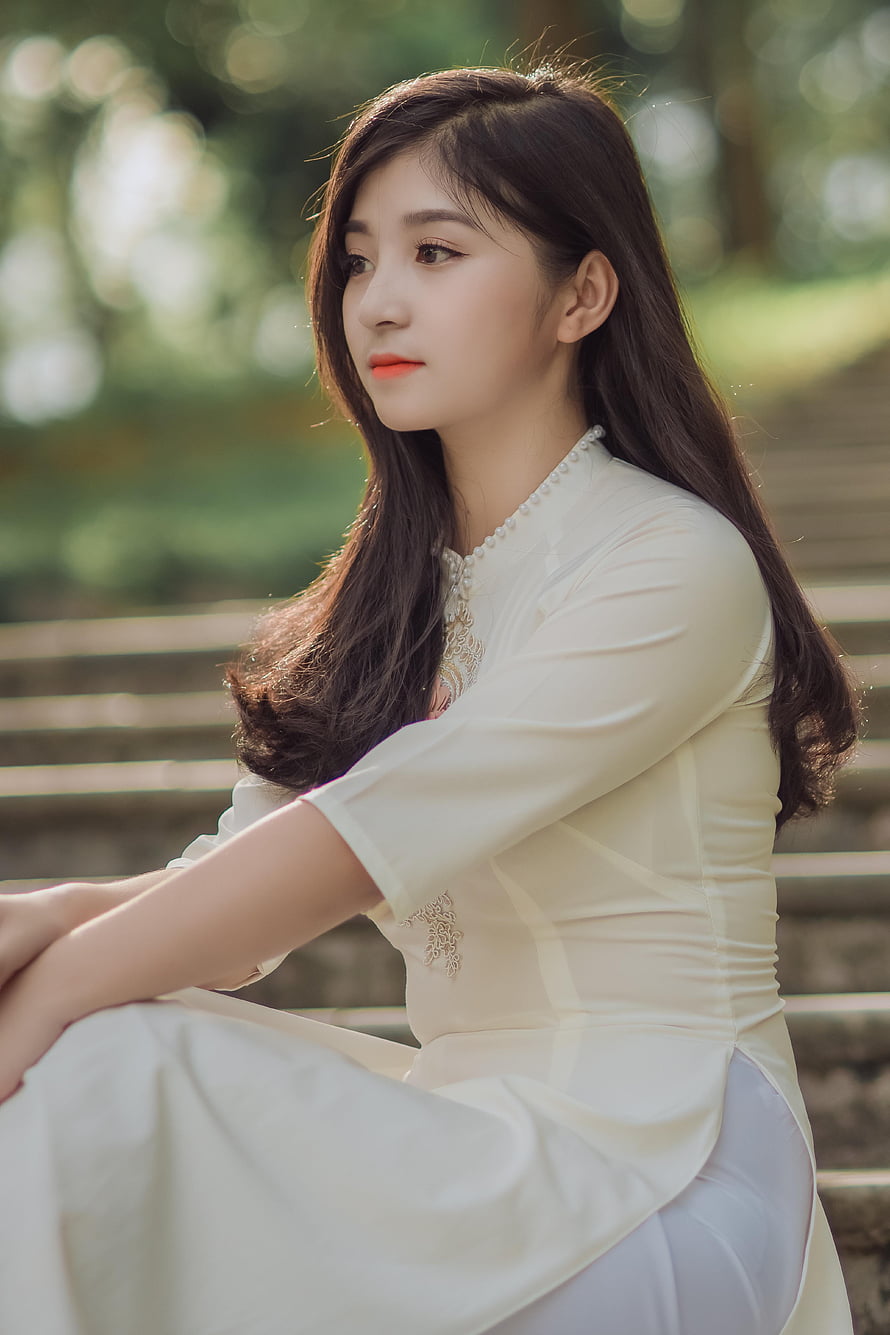 Elegant Woman in Traditional White Dress Sitting on Stone Steps in a Park HD phone wallpaper