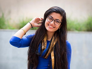 Rashmika Mandanna smiling portrait wearing glasses and a blue top with a patterned scarf HD wallpaper