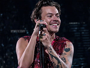 Harry Styles performing on stage in a red sequined outfit with microphone HD wallpaper