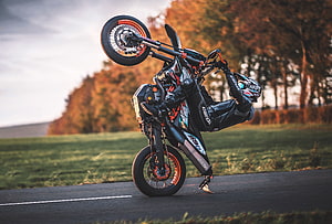 Supermoto Rider Performing Stunt on Gravel Road with Autumn Trees HD wallpaper