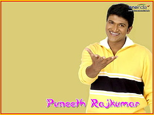 Puneeth Rajkumar in a yellow sweater with a warm smile and welcoming gesture HD wallpaper
