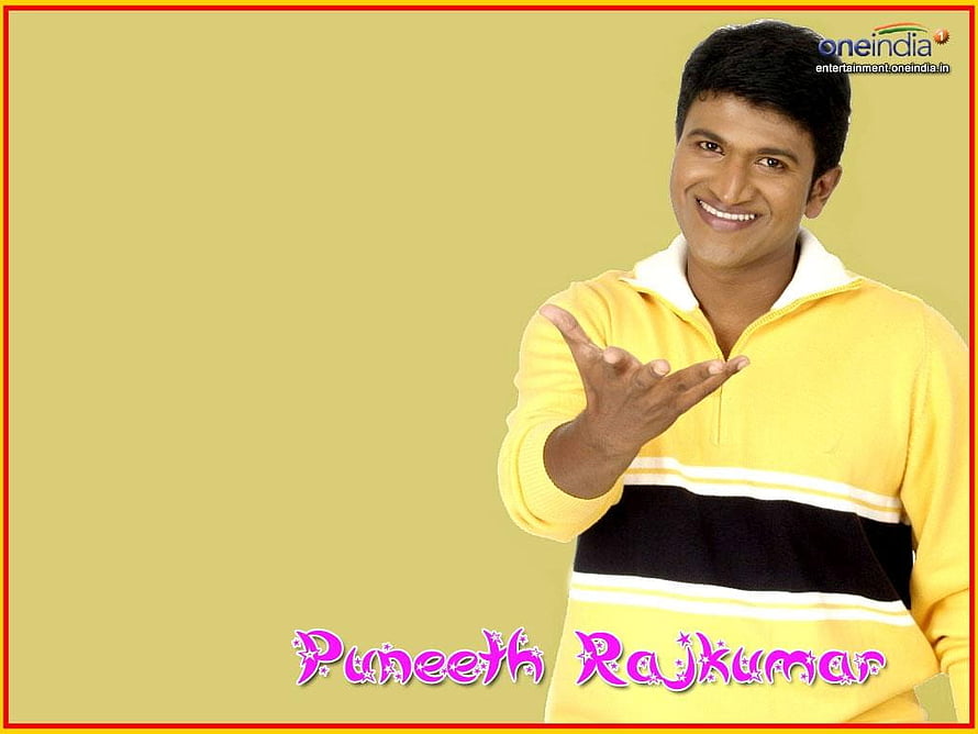 Puneeth Rajkumar in a yellow sweater with a warm smile and welcoming gesture HD wallpaper
