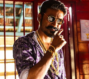 Dhanush in Maari wearing round sunglasses and gold chains in a purple patterned shirt HD wallpaper