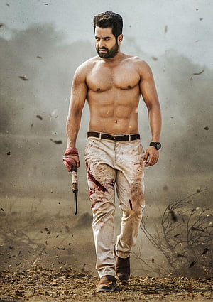 Jr NTR shirtless action still with bloodied pants and knife in dusty battlefield HD phone wallpaper