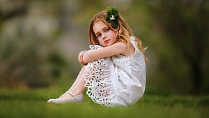 Young Girl in White Lace Dress Sitting on Grass with Flower in Hair HD wallpaper