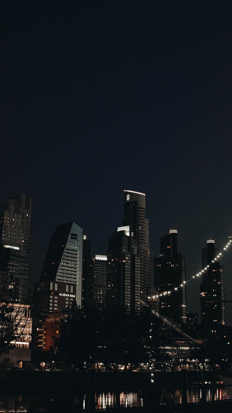 Moody Urban Skyline at Night with Illuminated High-Rise Buildings and Water Reflections HD phone wallpaper