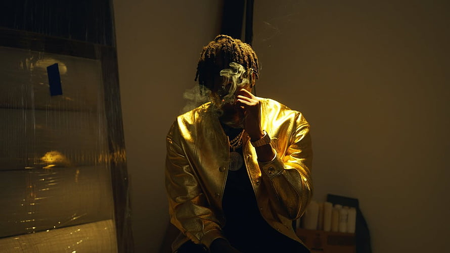 NBA YoungBoy in Gold Jacket Smoking in Moody Studio Setting HD wallpaper