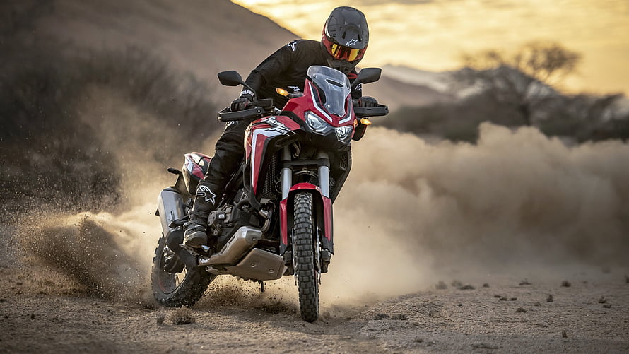 Rider on a Red Honda Africa Twin Adventure Motorcycle Kicking Up Dust on a Desert Trail at Sunset HD wallpaper
