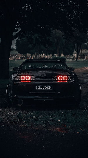 Rear View of a Black Toyota Supra with Glowing Red Taillights in a Dark Forest Setting HD phone wallpaper