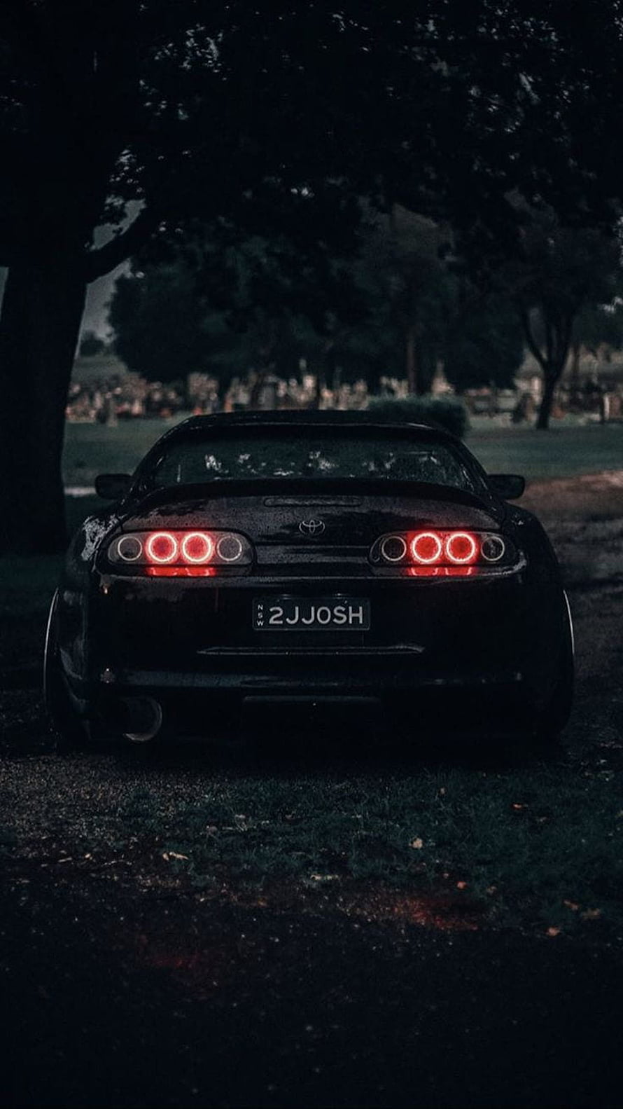 Rear View of a Black Toyota Supra with Glowing Red Taillights in a Dark Forest Setting HD phone wallpaper