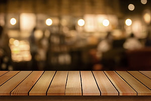 Warm wooden table surface with soft bokeh lights in a cozy cafe interior HD wallpaper