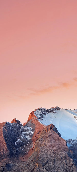 Alpine Mountain Peak with Snow and Rock Formations Under a Soft Pink Sky HD phone wallpaper