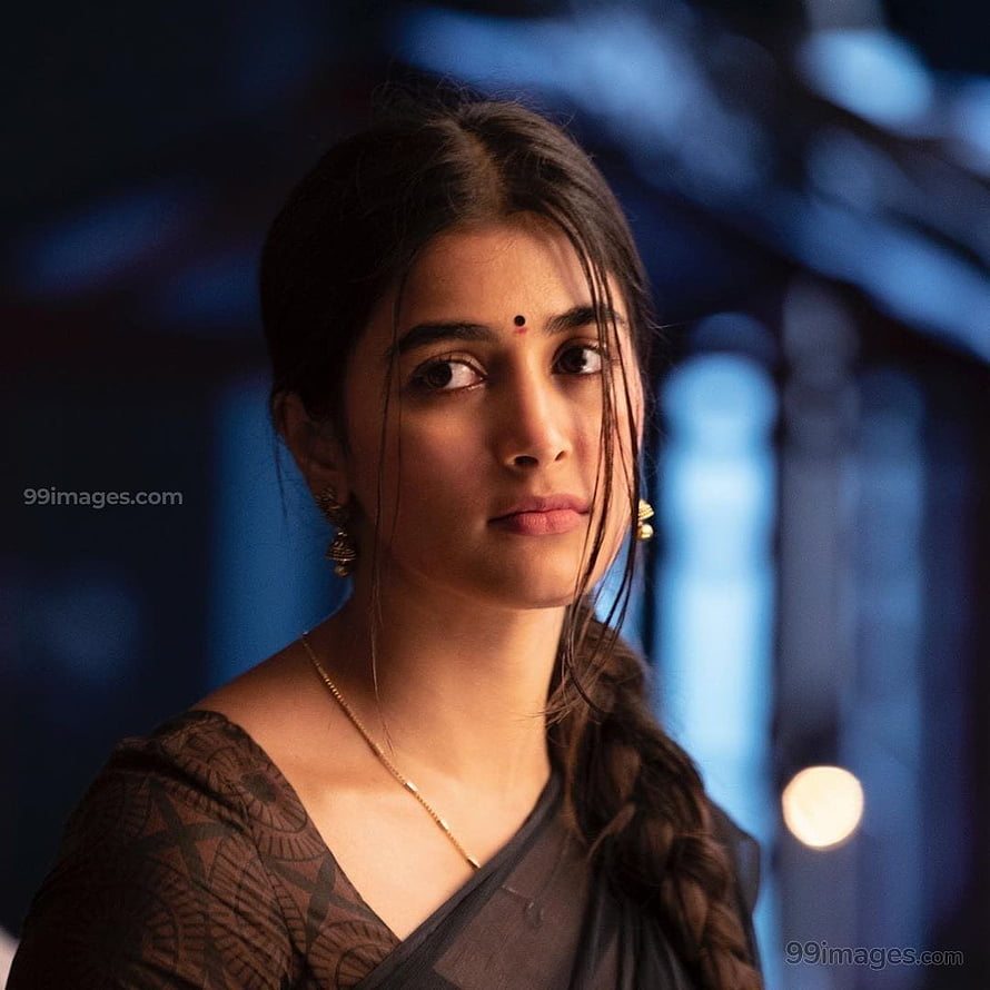 Pooja Hegde in a dark sari with a long braid and gold jewelry against a blue bokeh background HD phone wallpaper