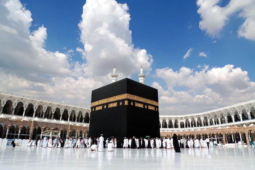 The Sacred Kaaba in Mecca with Pilgrims Performing Tawaf Under a Bright Blue Sky HD wallpaper