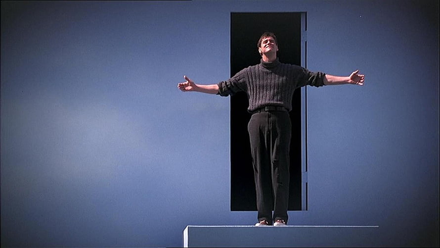 The Truman Show cinematic still of a man standing on a platform with arms outstretched against a blue wall HD wallpaper