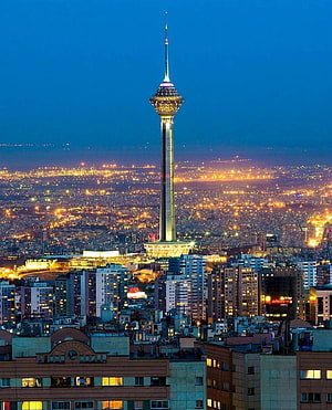 Milad Tower Illuminated at Dusk Over the Tehran Cityscape in Iran HD phone wallpaper