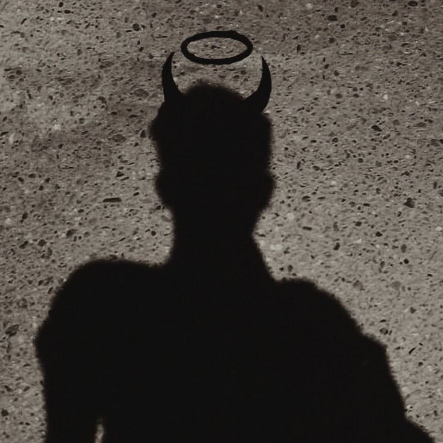 Dark silhouette of a horned figure with a halo against a textured concrete wall HD phone wallpaper