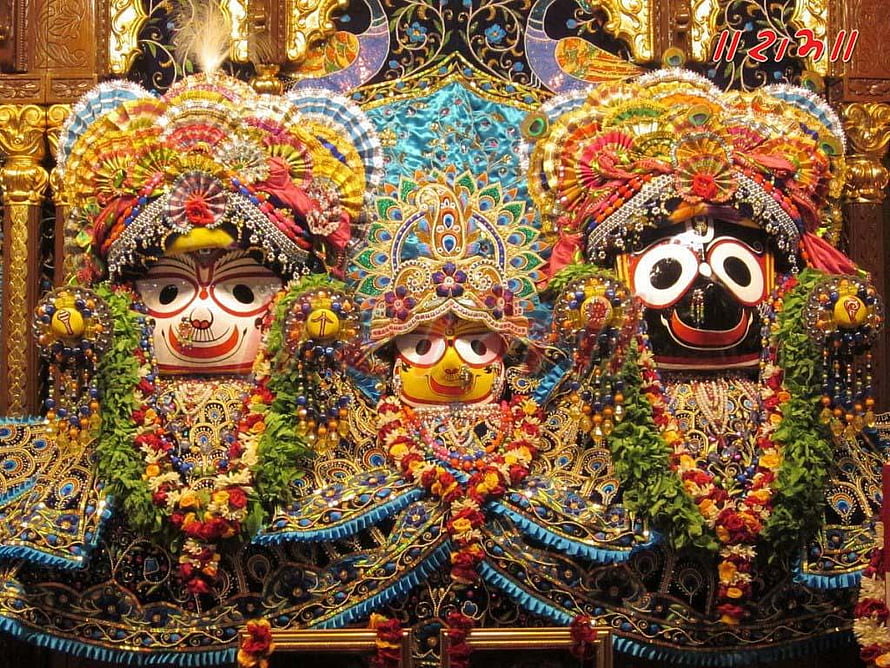 Lord Jagannath Deity with Ornate Headdresses and Floral Garlands in Temple Setting HD wallpaper