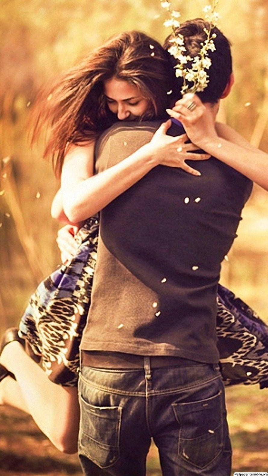 Romantic couple embracing in a golden field with white flowers HD phone wallpaper