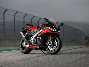 Aprilia RSV4 Factory sportbike parked on a racetrack with red and black livery HD wallpaper