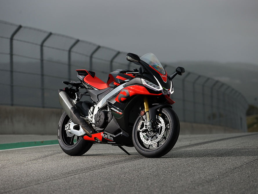 Aprilia RSV4 Factory sportbike parked on a racetrack with red and black livery HD wallpaper